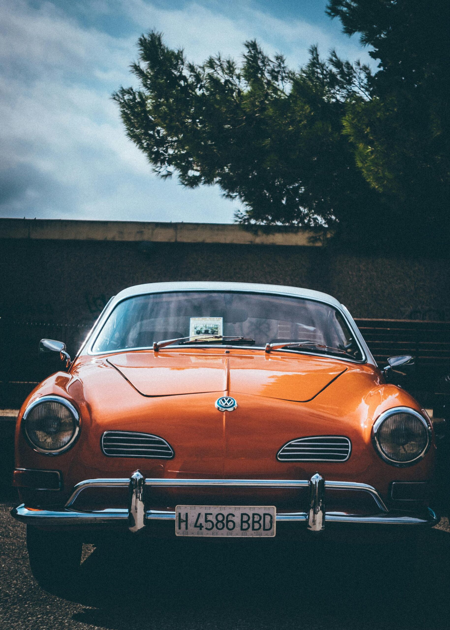 Front view of an orange vintage Volkswagen car parked outdoors with a nostalgic vibe.
